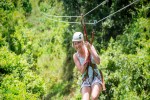 Beautiful happy woman riding a zip line in a lush tropical forest while on family vacation. Having fun and smiling with excitement banner iStock 532255430